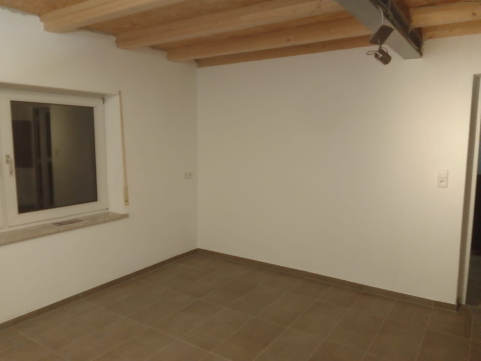 Frisch renovierter Raum mit Holzbalken und Fliesenboden