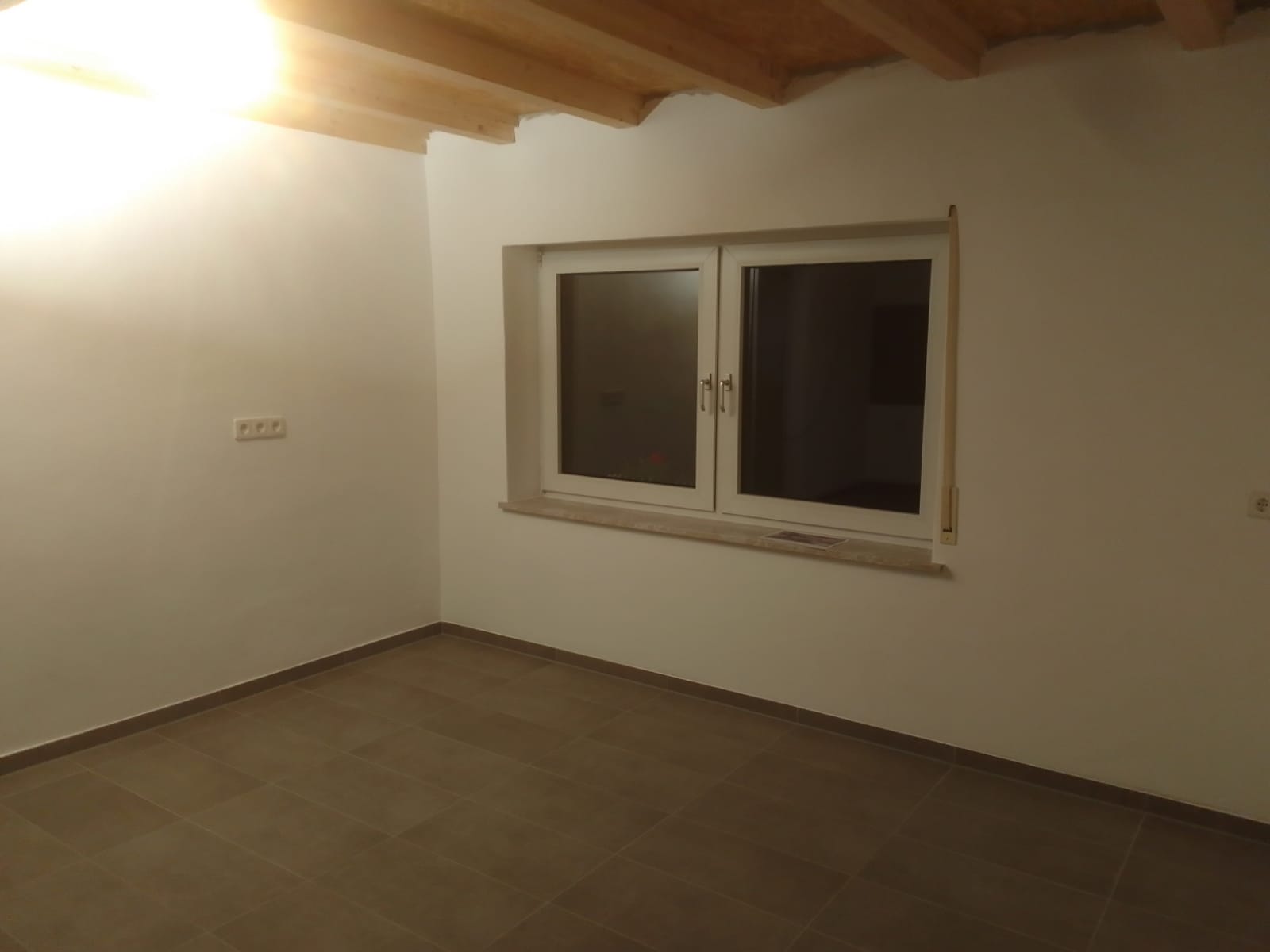 Renovierter Raum mit Fenster und Holzbalkendecke